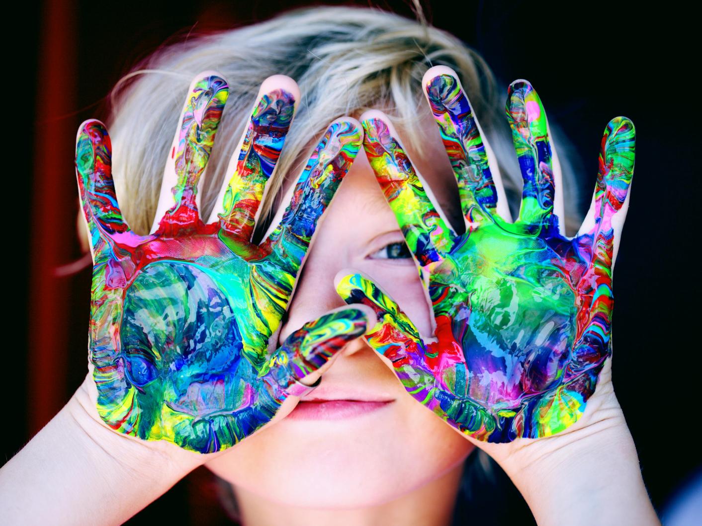 A kid with multi-coloured hand paint