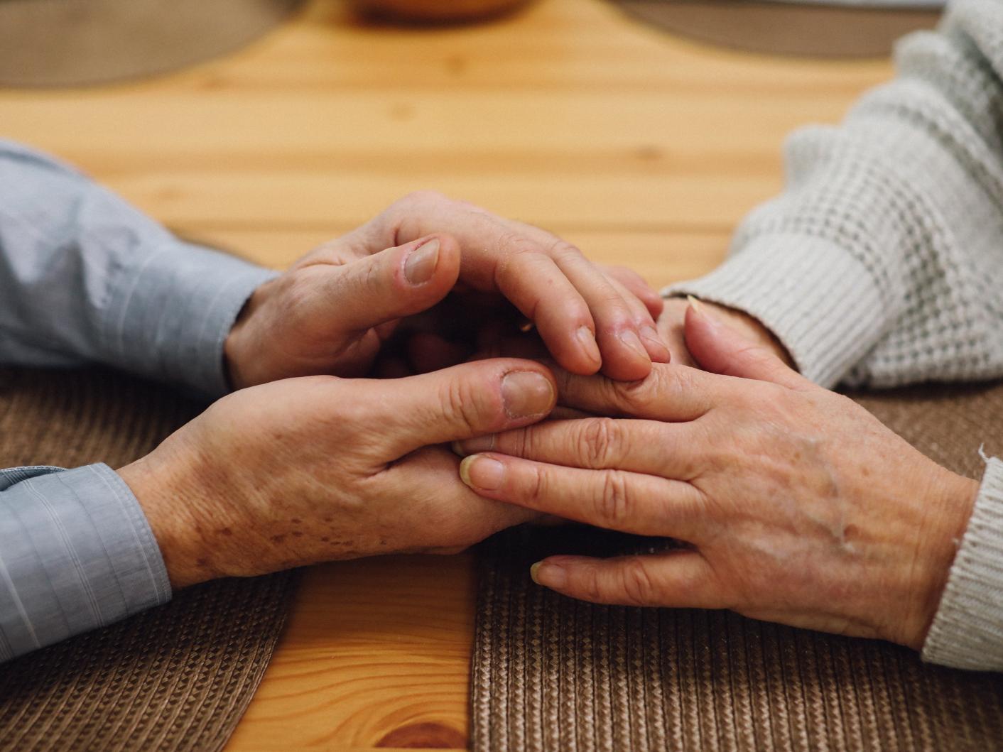 Photo of an elderly lady holding hands with a younger lady